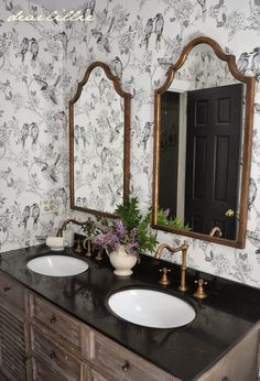 a bathroom with two sinks, mirrors and flowers on the counter top in front of it