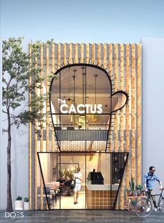 a man riding a bike past a tall building with a sign that reads the cactus