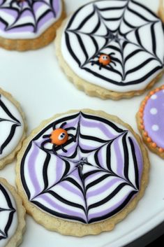 decorated cookies with spider webs and purple icing on a white platter for halloween