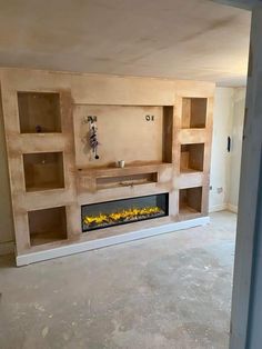 an empty living room with a fireplace in the center and shelves on either side that are built into the wall