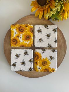 four bees and sunflowers are painted on small coasters next to a bouquet of flowers