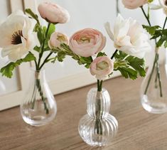 three clear vases with pink and white flowers in them