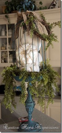 a birdcage filled with white balls and greenery on top of a counter