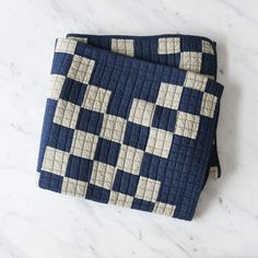 two blue and white quilts sitting on top of a marble countertop next to each other