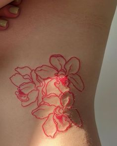 a woman's stomach with red ink on it and flowers drawn on the side