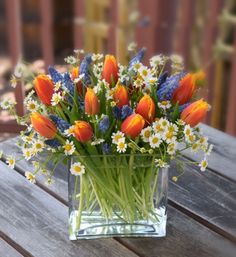 a vase filled with lots of flowers on top of a wooden table