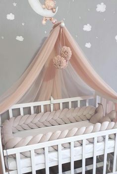 a baby crib with a teddy bear hanging from it's canopy