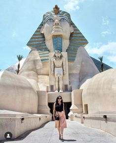 a woman standing in front of an egyptian statue