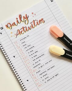 two pens sitting on top of a notebook with the words daily activities written in it