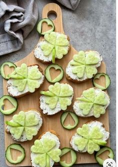 small sandwiches with cucumber and cream cheese are arranged on a cutting board