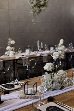 the table is set with white flowers and place settings for an event or wedding reception