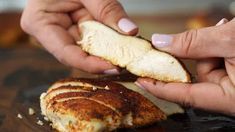 a woman is peeling an apple slice into her chicken breast, which has been cut in half and placed on a cutting board