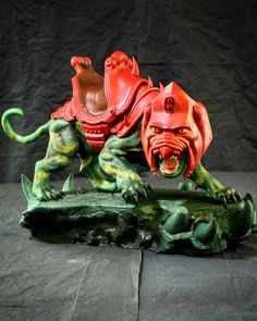 a red and green figurine on a black surface