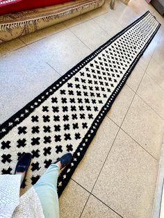 a person standing on the floor next to a black and white rug that is laying on the ground