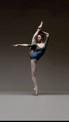 a ballerina in blue and green is doing a ballet move with her arms stretched out