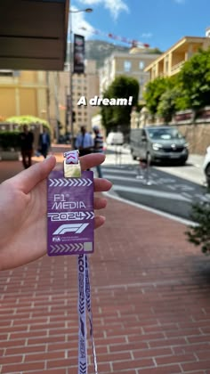 a person holding up a purple stick with the words dream on it in front of a brick sidewalk