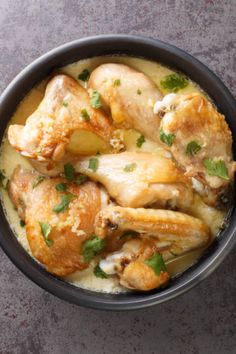 a black bowl filled with chicken and potatoes