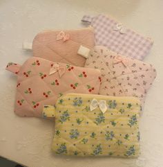 four small purses sitting on top of a white table next to eachother