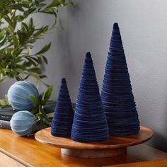 three blue cones sitting on top of a wooden table next to a book and plant