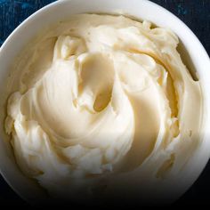 a white bowl filled with whipped cream on top of a blue table