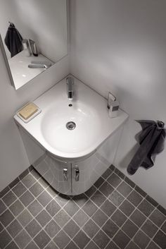 a white sink sitting next to a mirror on top of a tiled floor in a bathroom