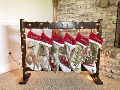 christmas stockings hanging from a rack in front of a brick wall with lights on it