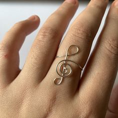 a woman's hand with a ring on it that has a musical note in the middle