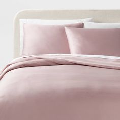 a bed with pink sheets and pillows on it