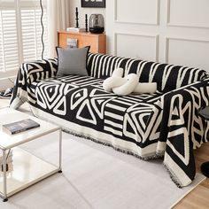 a black and white couch sitting in a living room next to a window with shutters