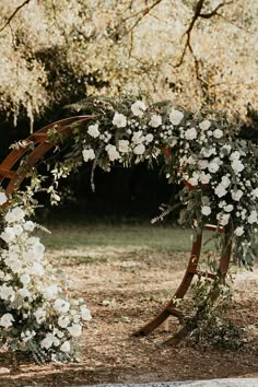 an outdoor wedding arch with white flowers and greenery