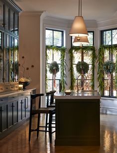 a kitchen with an island and lots of plants in the window sill, along with two chairs