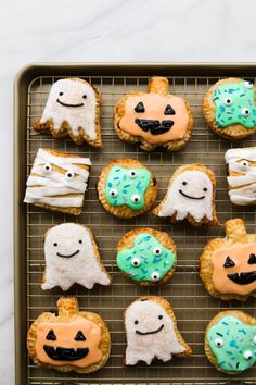 halloween cookies decorated with icing and sprinkles on a cooling rack for display