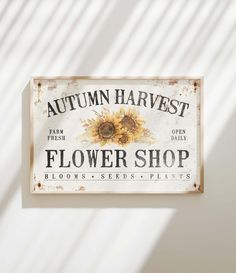 a sign that says autumn harvest flower shop on the side of a building with sunflowers painted on it