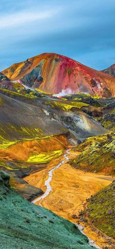 the hills are covered in colorfully colored grass and dirt, with a stream running between them