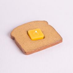 a yellow candle sitting on top of a piece of bread