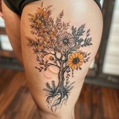 a woman's thigh with a tree and flowers on it