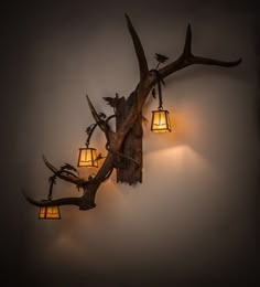 an antler with three lamps on it hanging from the side of a white wall