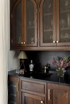 a kitchen with wooden cabinets and black counter tops, along with vases filled with flowers