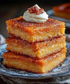 three pieces of cake sitting on top of a blue and white plate topped with whipped cream