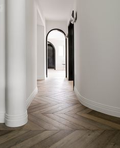 an empty hallway with white walls and wood flooring