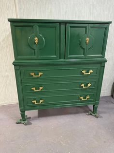 a green dresser with gold handles and knobs on the doors is sitting in a room