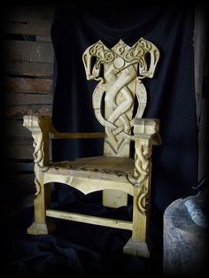 a wooden chair with an intricate design on it's back and arms, sitting in front of a black background