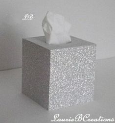 a tissue dispenser sitting on top of a white counter next to a wall