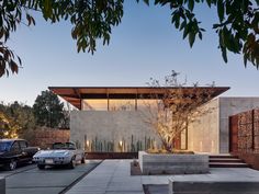 two cars are parked in front of a modern house with cactus and cacti