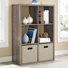 a bookcase with three bins in front of a window and a vase on top