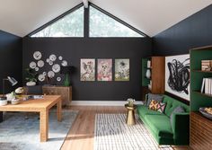 a living room with black walls and green furniture in the center, along with pictures on the wall