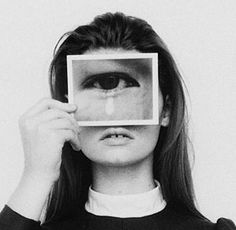 a woman holding up a square object in front of her face to look through it