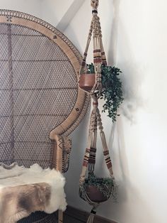 a wicker chair with plants hanging from it's back and on the wall