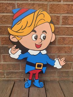 a wooden cutout of a cartoon character on a wood floor next to a brick wall