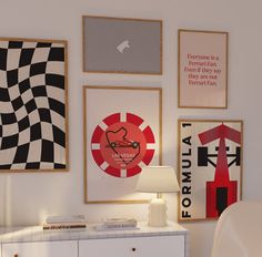 a room with posters on the wall and a white dresser in front of it that has a lamp next to it